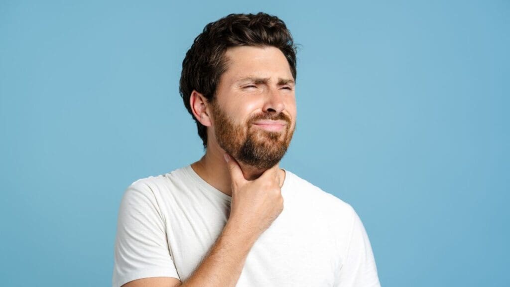 homem-branco-com-barba-colocando-a-mão-pescoço-com-dor-de-garganta-shutterstock