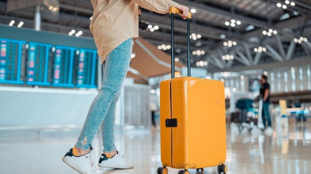 mulher-jovem-andando-com-mala-de-viagem-no-aeroporto-shutterstock