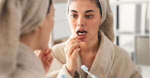 mulher-jovem-escovando-dentes-olhando-no-espelho