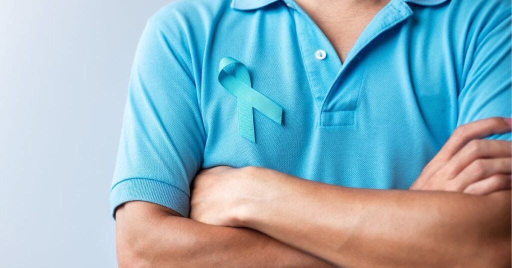 Homem de camisa azul com laço azul em apoio a pessoas com doenças.