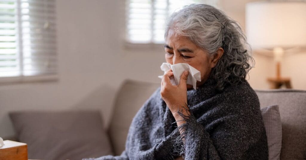 mulher-idosa-no-sofa-assoando-nariz-alergias-gripe-influenza