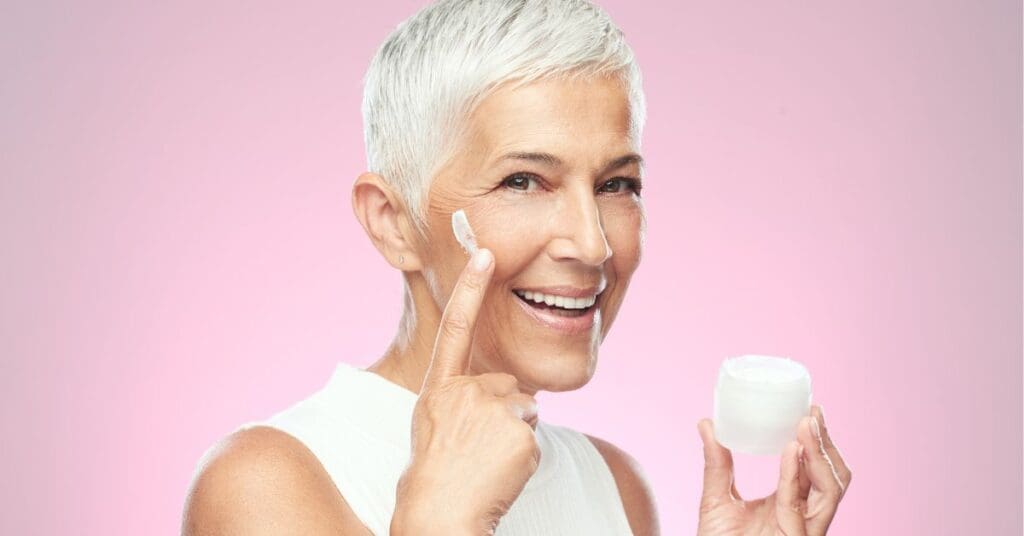 mulher-senior-sorrindo-passando-creme-no-rosto-dermocosmetico